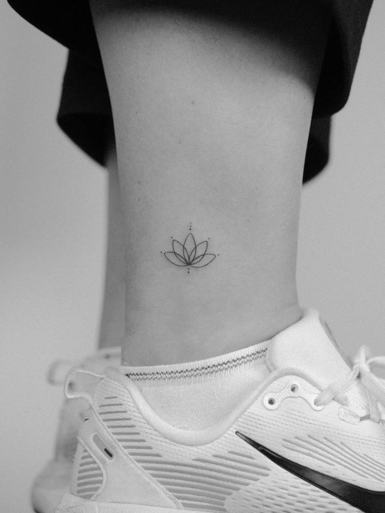Fine line style little lotus flower tattoo located on the ankle.