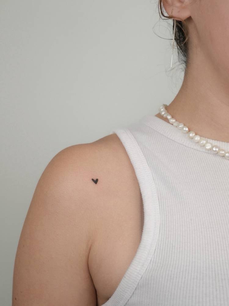 Minimalistic micro heart tattoo located on the shoulder.
