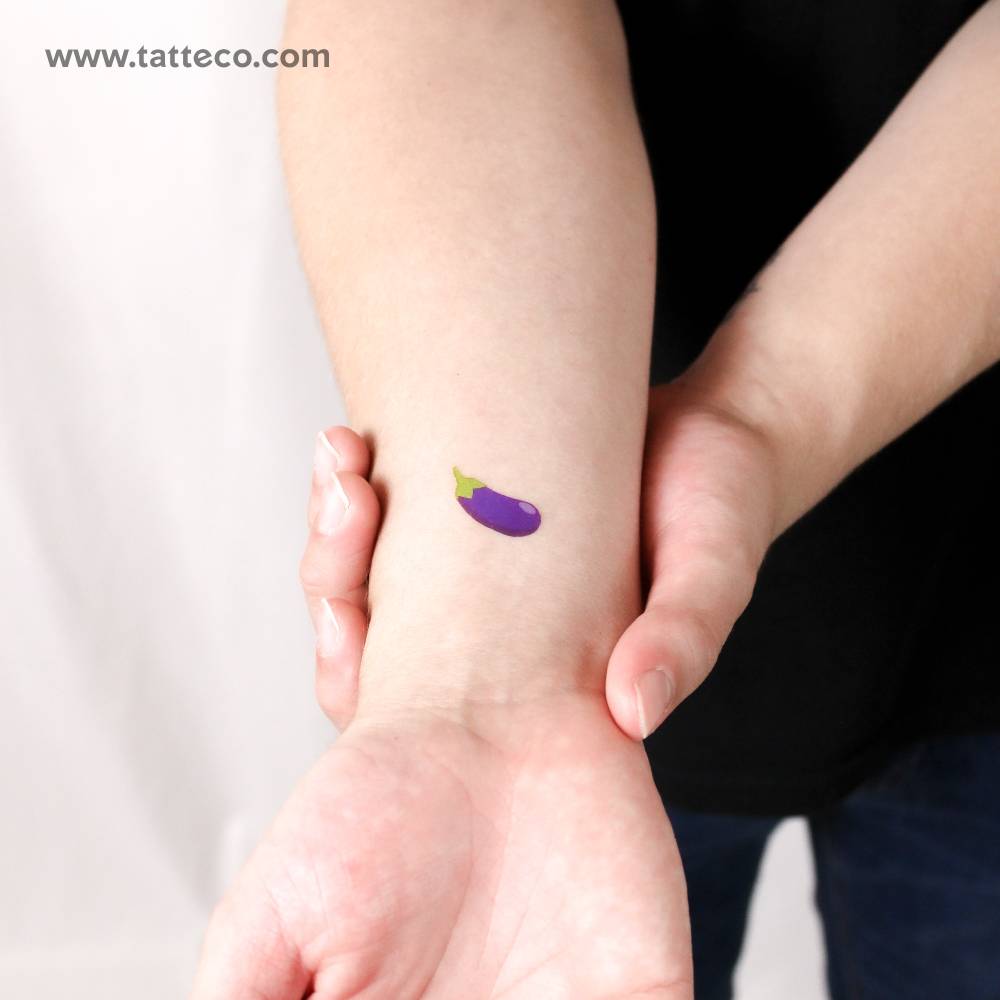 Small eggplant emoji temporary tattoo located on the wrist.