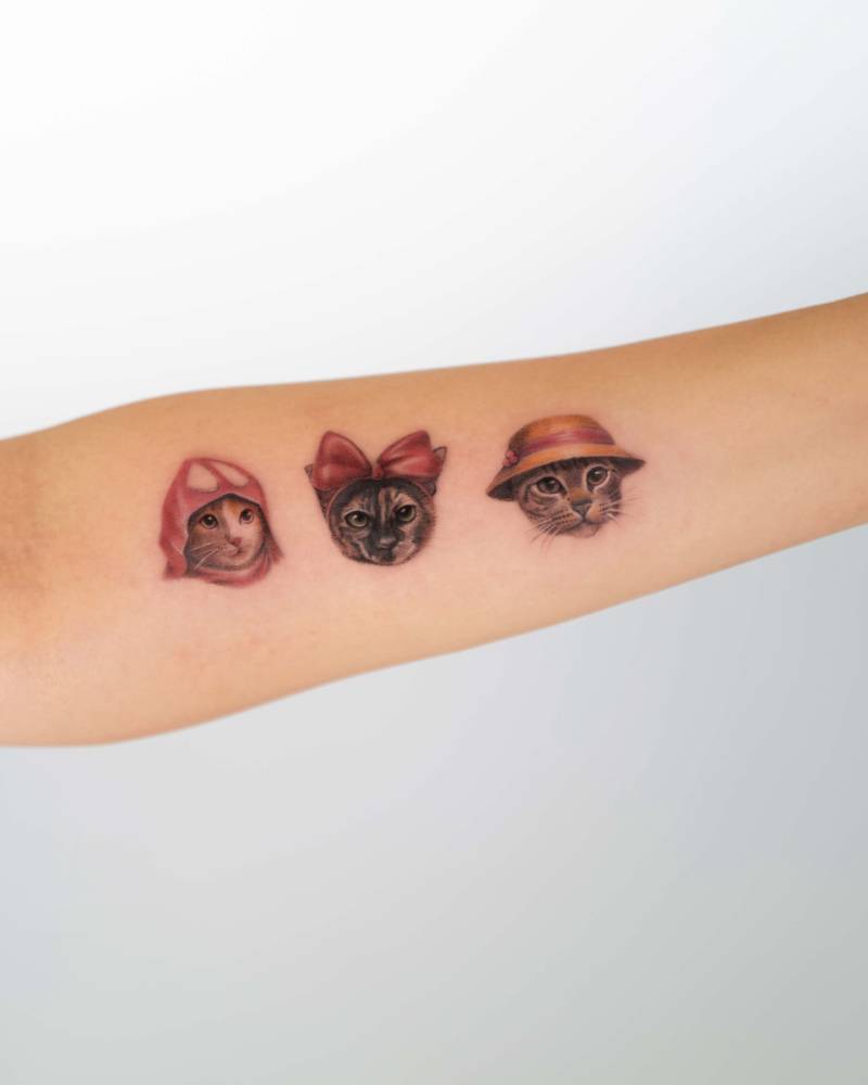 Ghibli cats tattooed on the inner forearm, micro-realistic style.