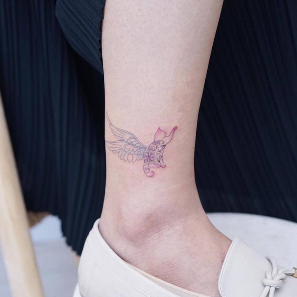 Watercolor winged cat tattoo on the ankle.