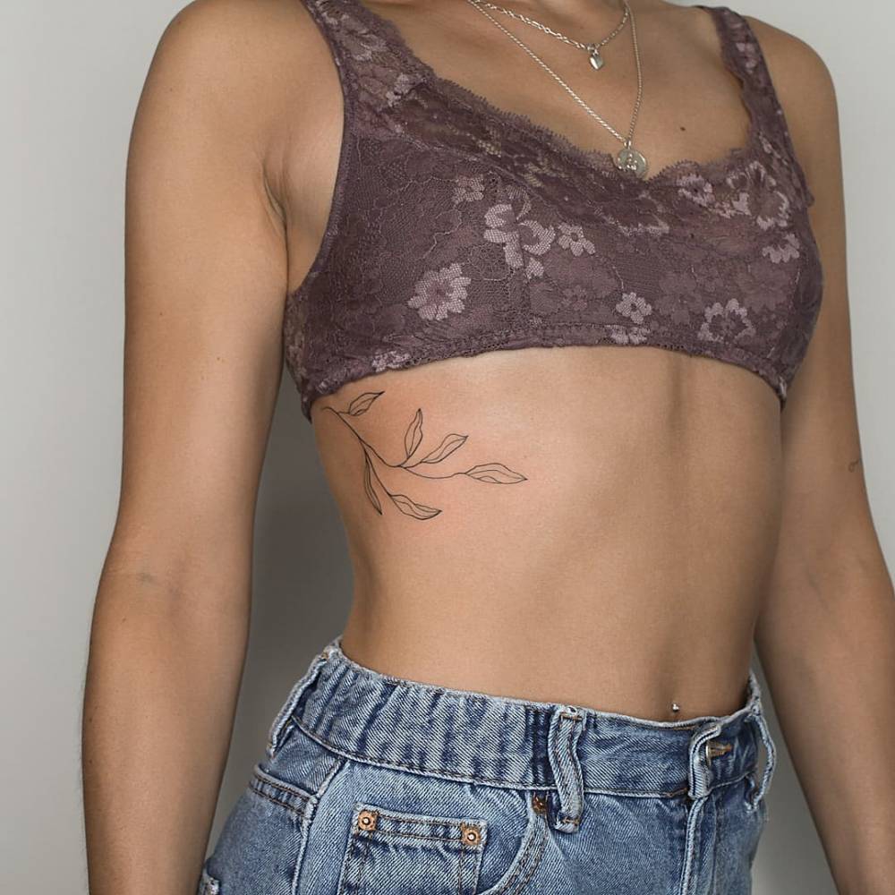 Fine line leaves tattoo located on the rib.