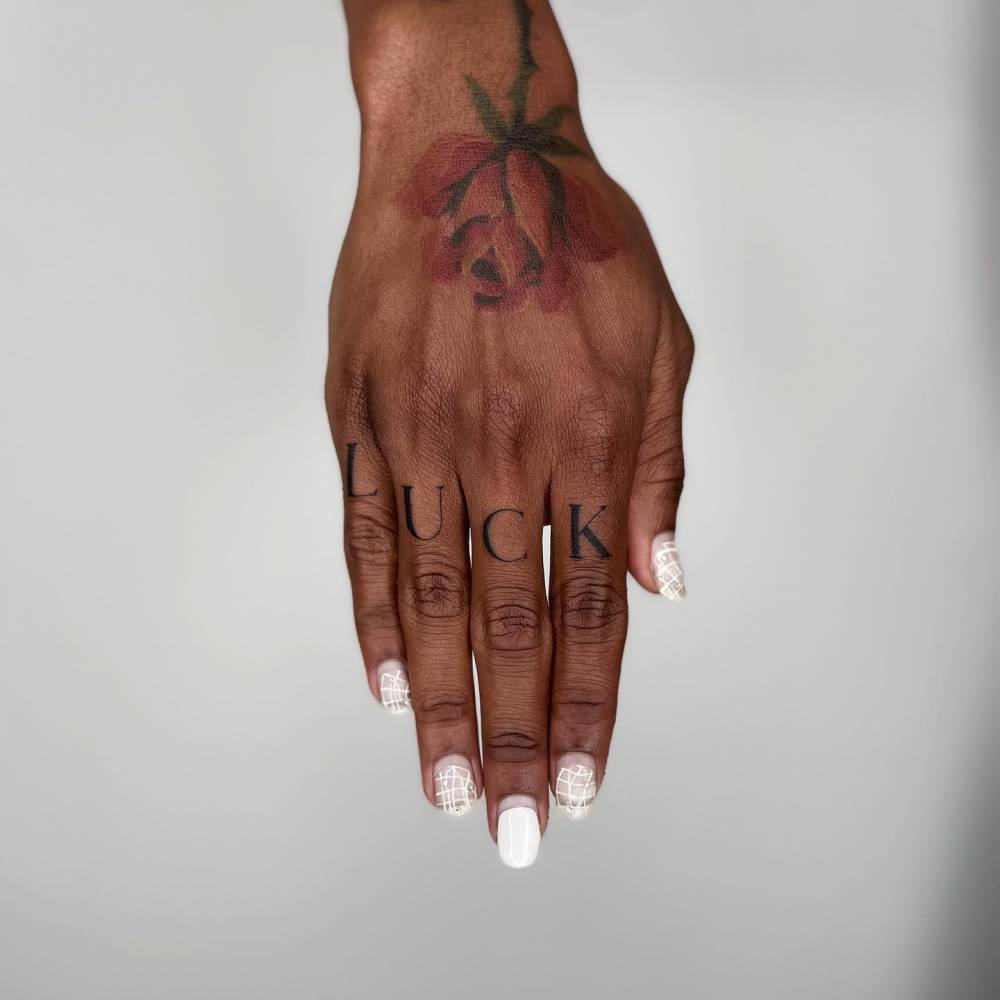 Tattoo of the word "luck" located on the knuckles.