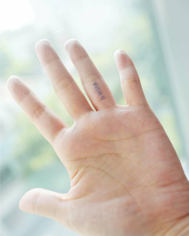 Lettering tattoo in blue ink done on the finger.