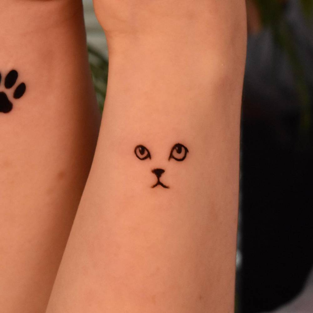 Minimalistic cat tattoo located on the wrist.