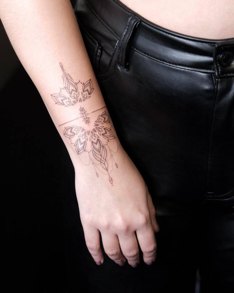Ornamental bracelet tattoo located on the wrist, fine line style.