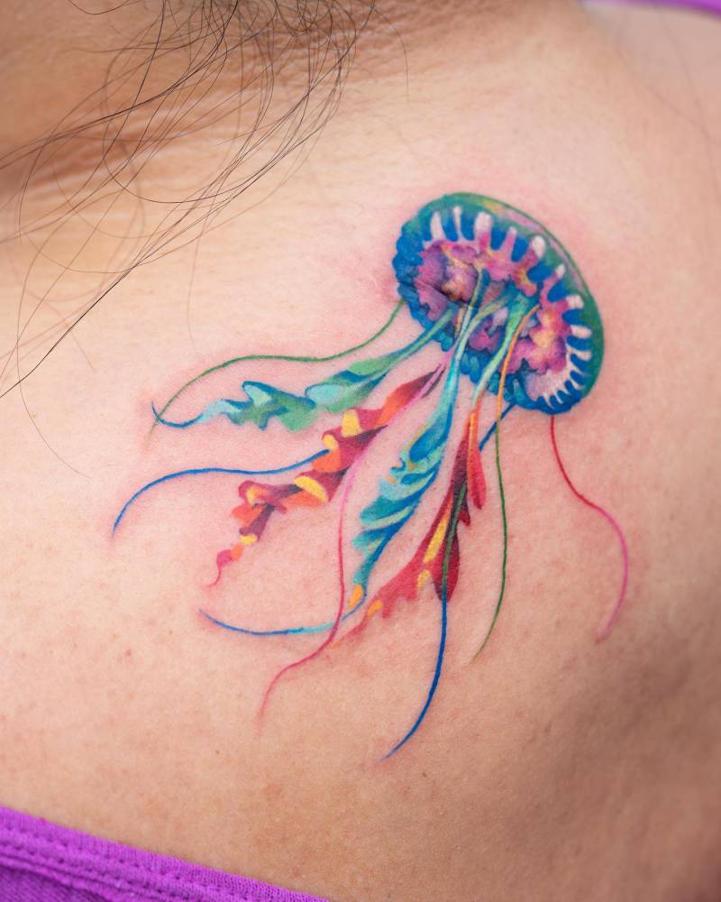 Watercolor style jellyfish tattoo placed on the upper back.