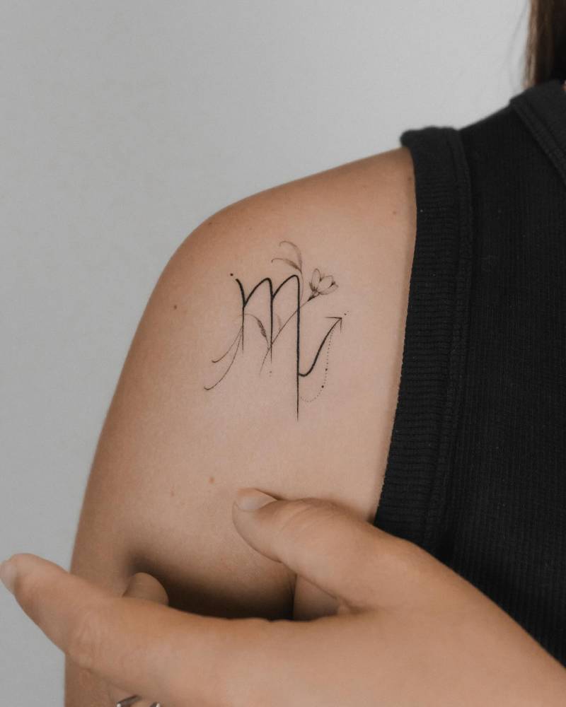 Scorpio zodiac symbol tattooed on the shoulder, illustrative style.