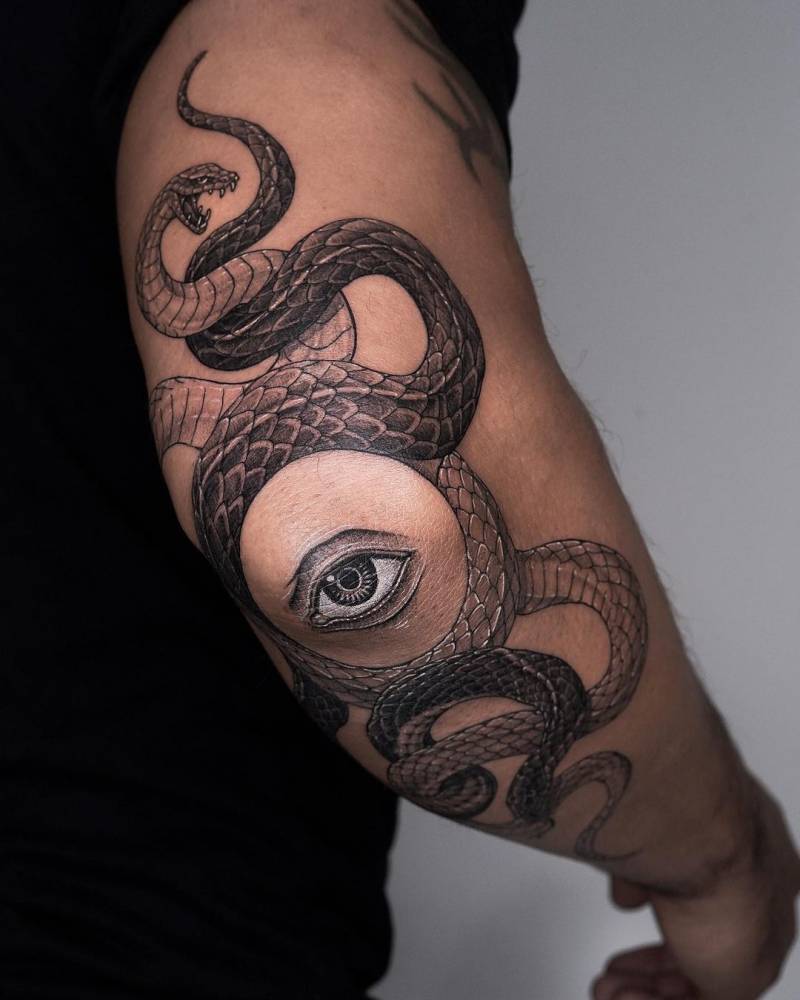 Illustrative style snakes and eye tattooed on the elbow.