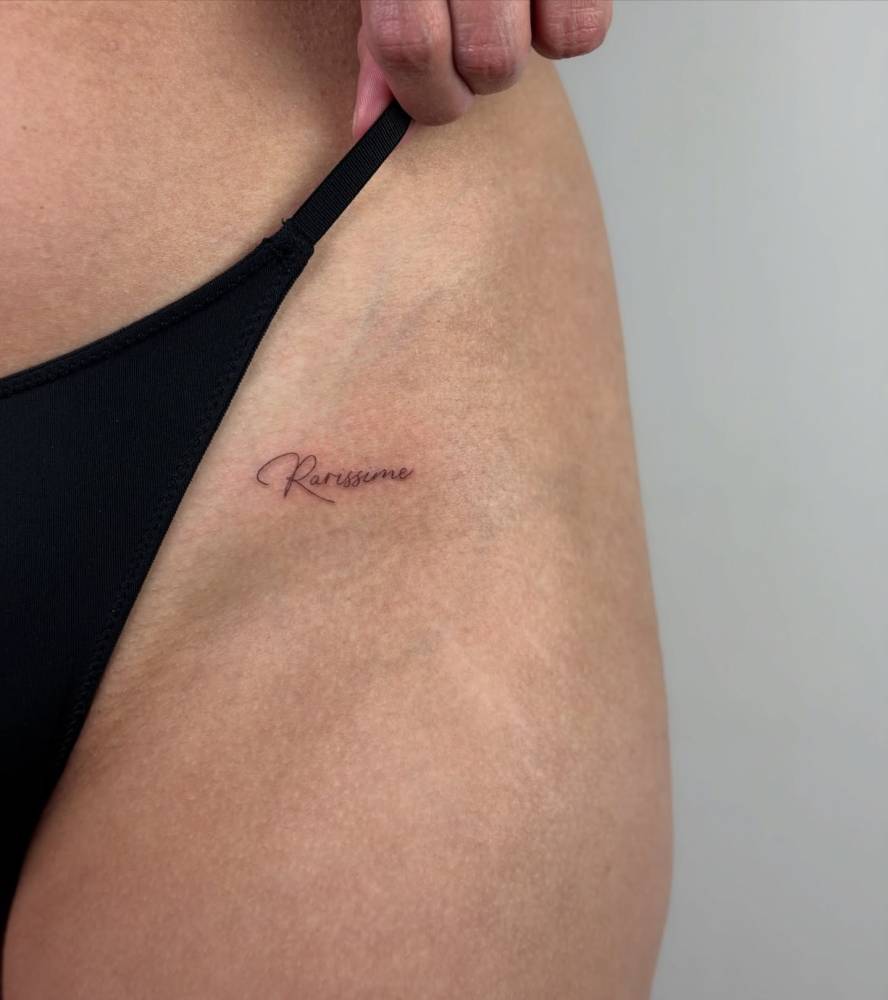 "Rarissime" lettering tattoo located on the pelvis.