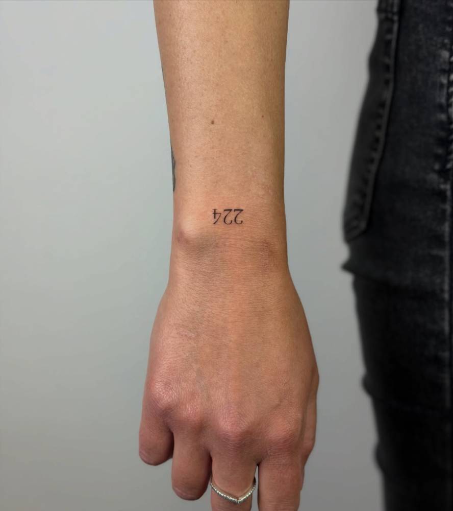 Tattoo of the number "224" located on the wrist.