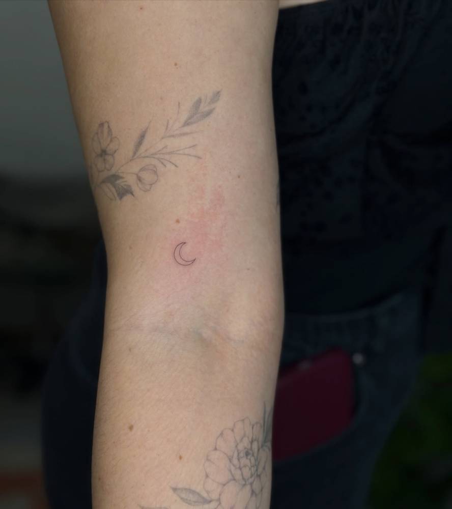 Tiny minimalistic crescent moon tattoo done on the bicep.