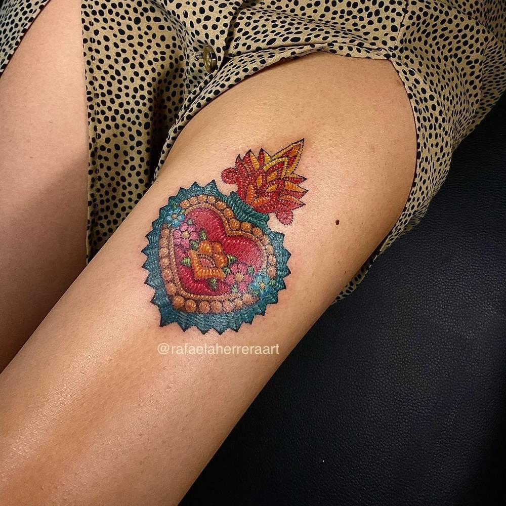 Mexican embroidery flaming heart tattoo located on the thigh.
