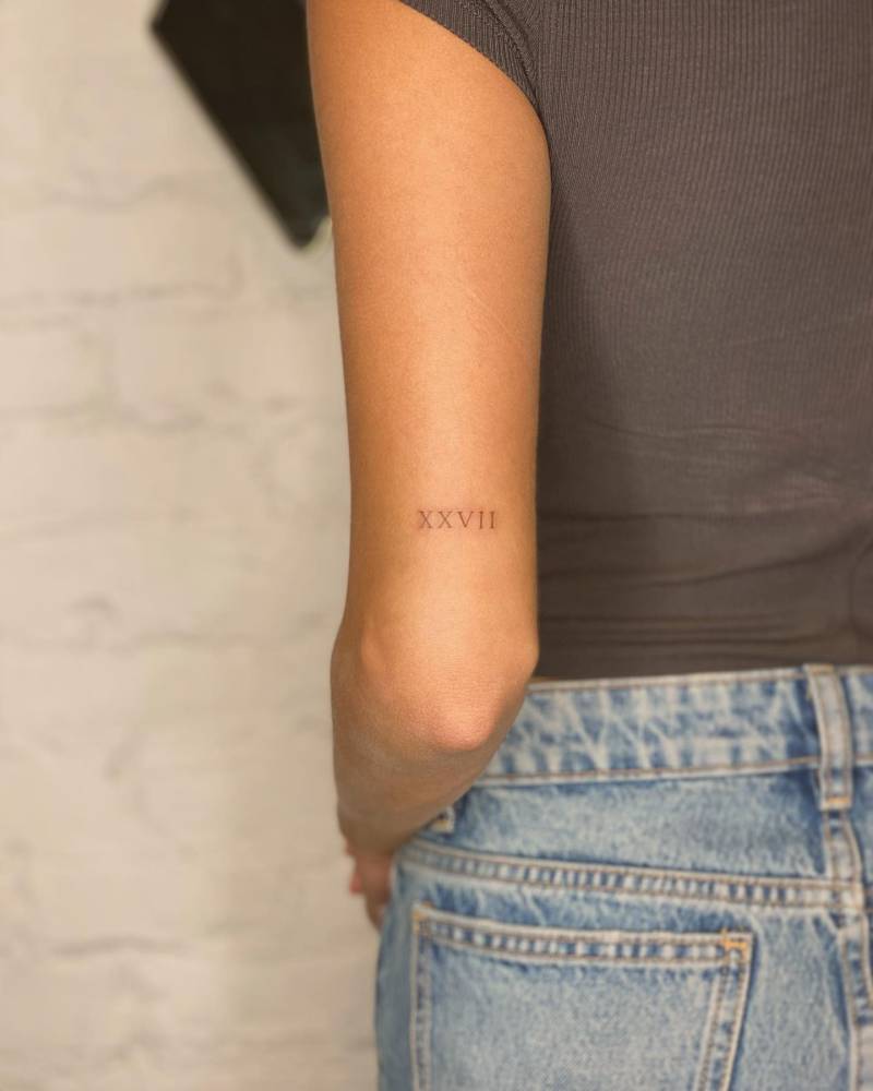 Roman numeral tattoo located on the tricep.