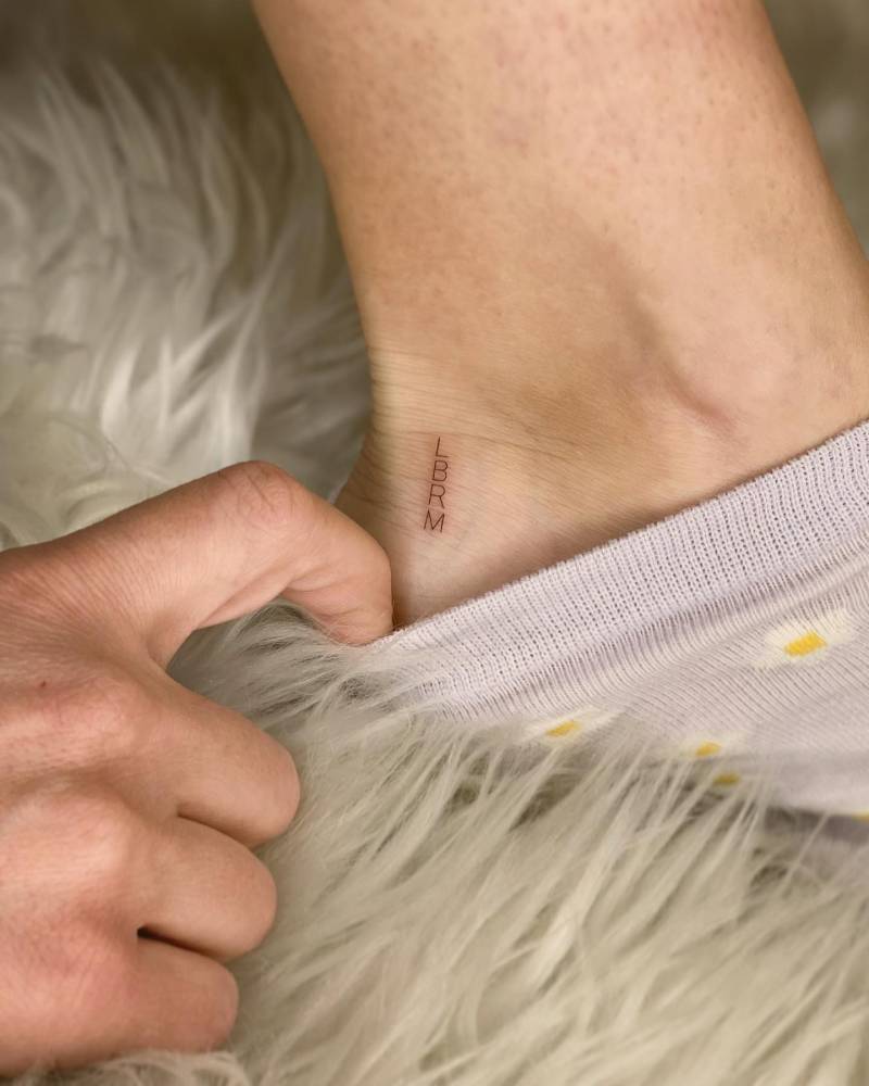 Tiny initials tattoo located on the ankle.