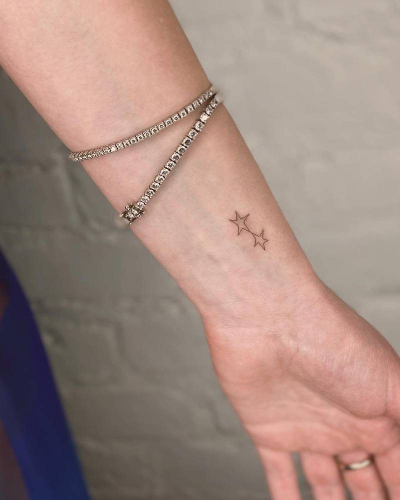 Little star couple tattoo located on the wrist, minimalistic style.