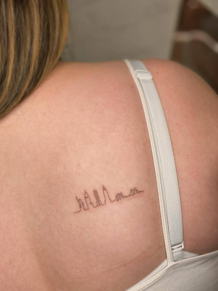 Once line New York City skyline tattoo placed on the shoulder blade.
