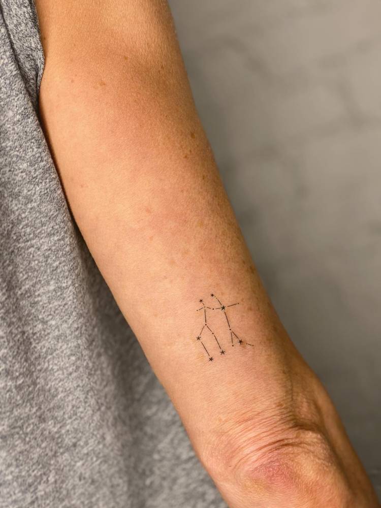 Gemini constellation tattoo done on the tricep, minimalistic style.