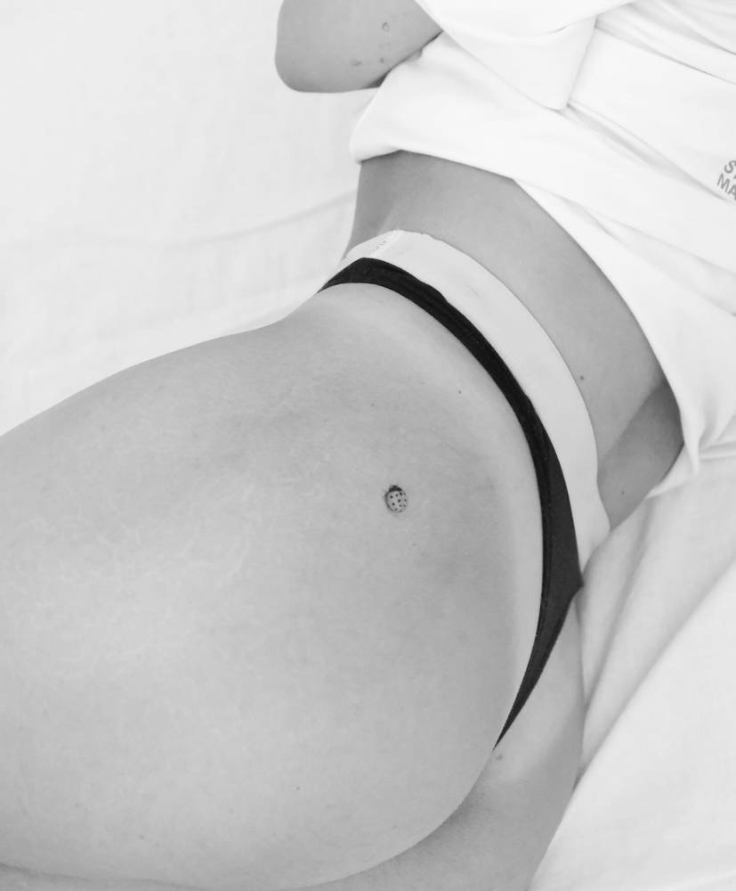 Single needle ladybug tattoo placed on the butt cheek.