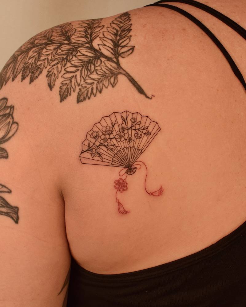 Cherry blossom hand fan tattoo in fine line style placed on the shoulder blade.