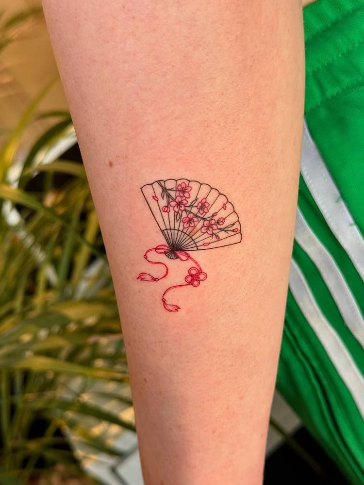 Hand fan and cherry blossom tattoo placed on the inner forearm.