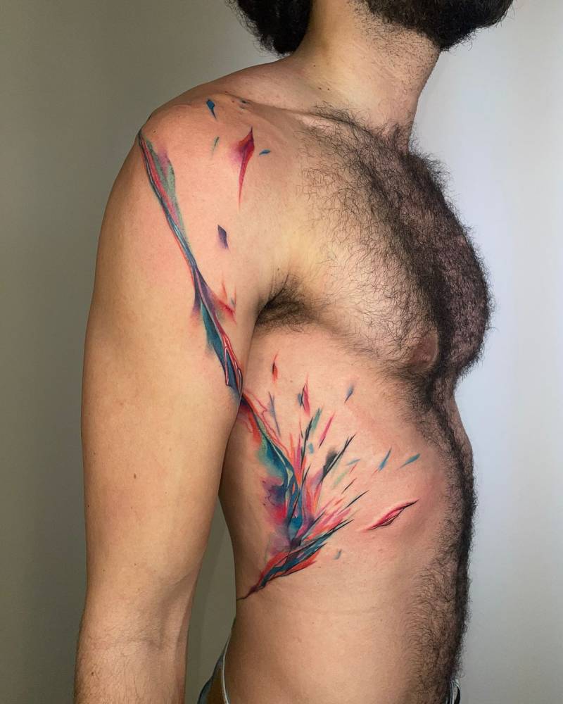 Watercolor style abstract design tattooed on the rib and upper arm.