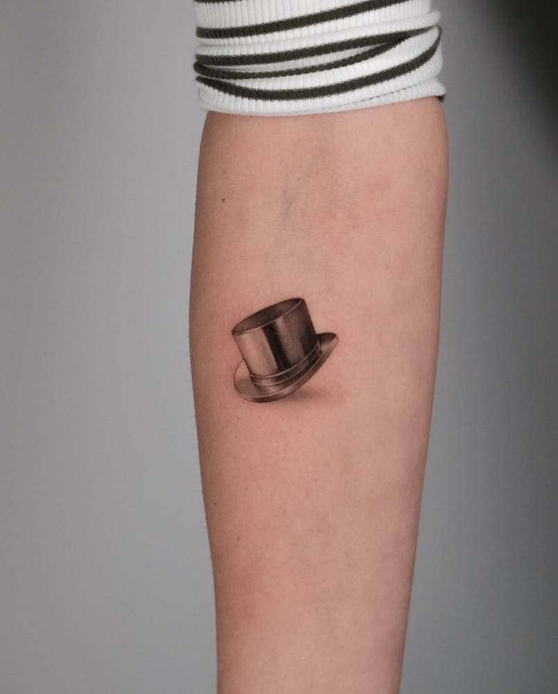 Monopoly's top hat tattoo located on the inner forearm.