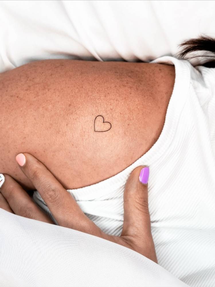 Tiny minimalistic heart tattoo placed on the shoulder.