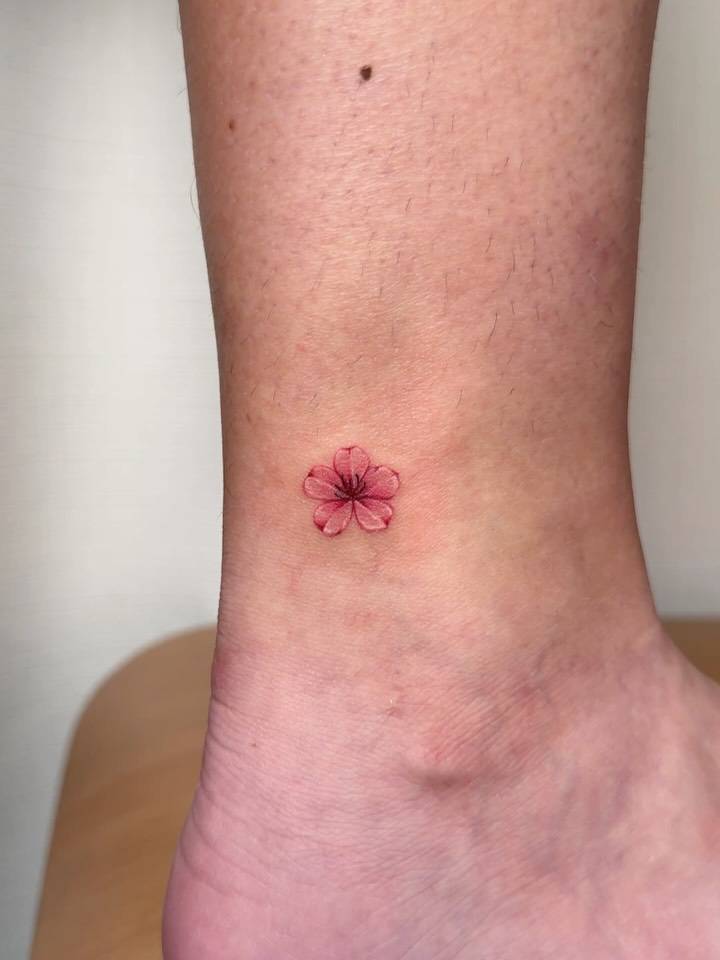 Watercolor style cherry blossom tattoo located on the ankle.