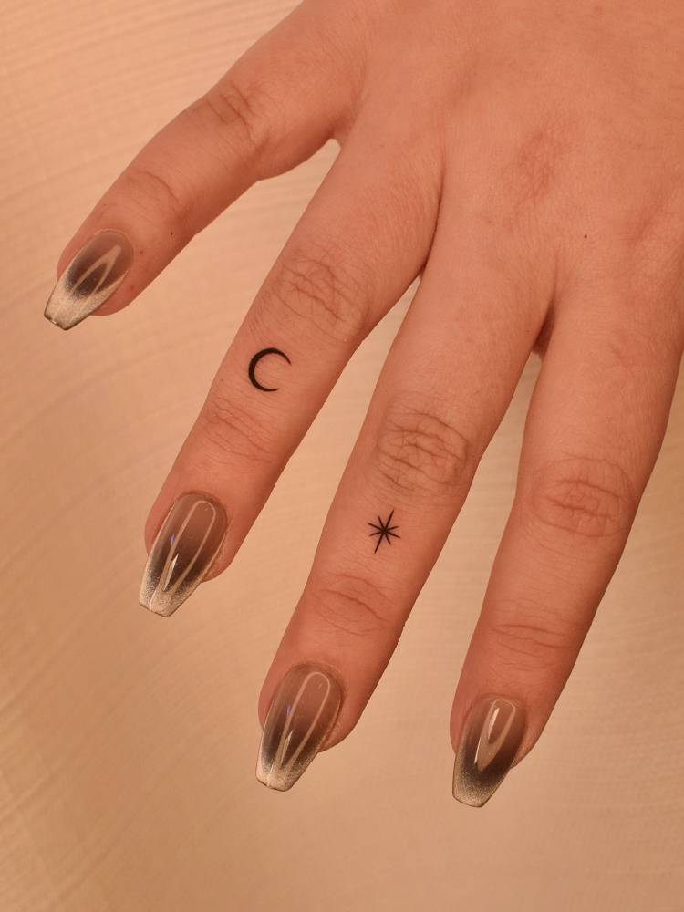 Minimalistic style crescent moon and north star tattoo located on the finger.