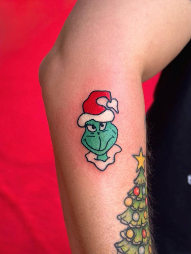 Grinch portrait tattoo hand poked on the forearm.