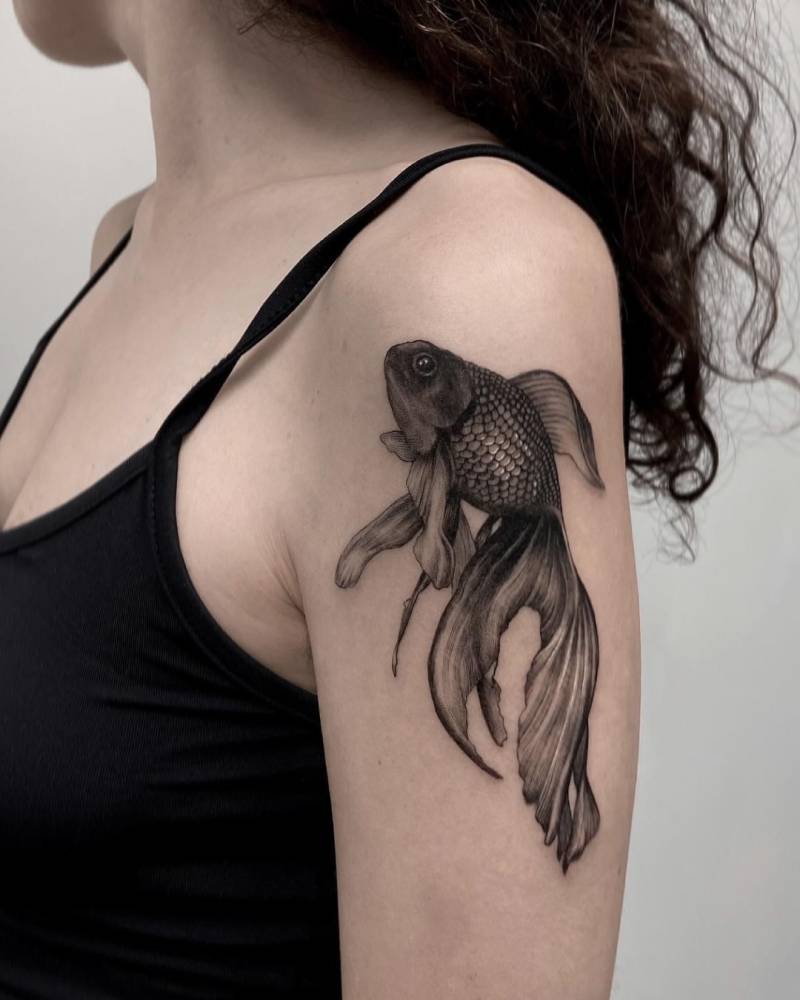 Goldfish tattoo located on the upper arm, black and grey style.
