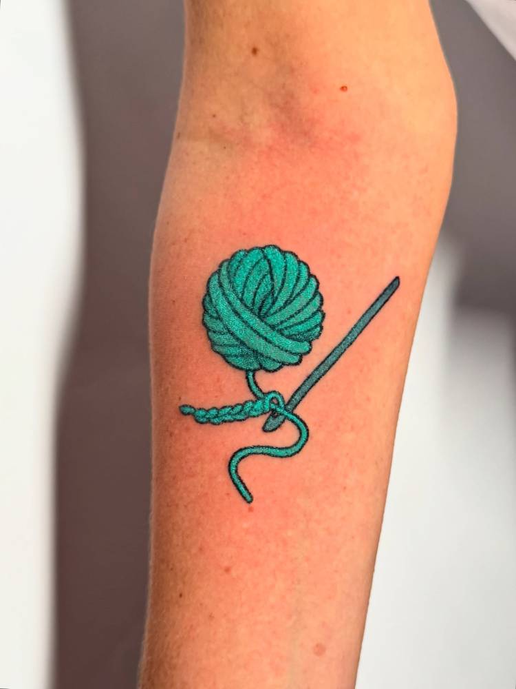 Hand poked wool yarn tattoo located on the inner forearm.