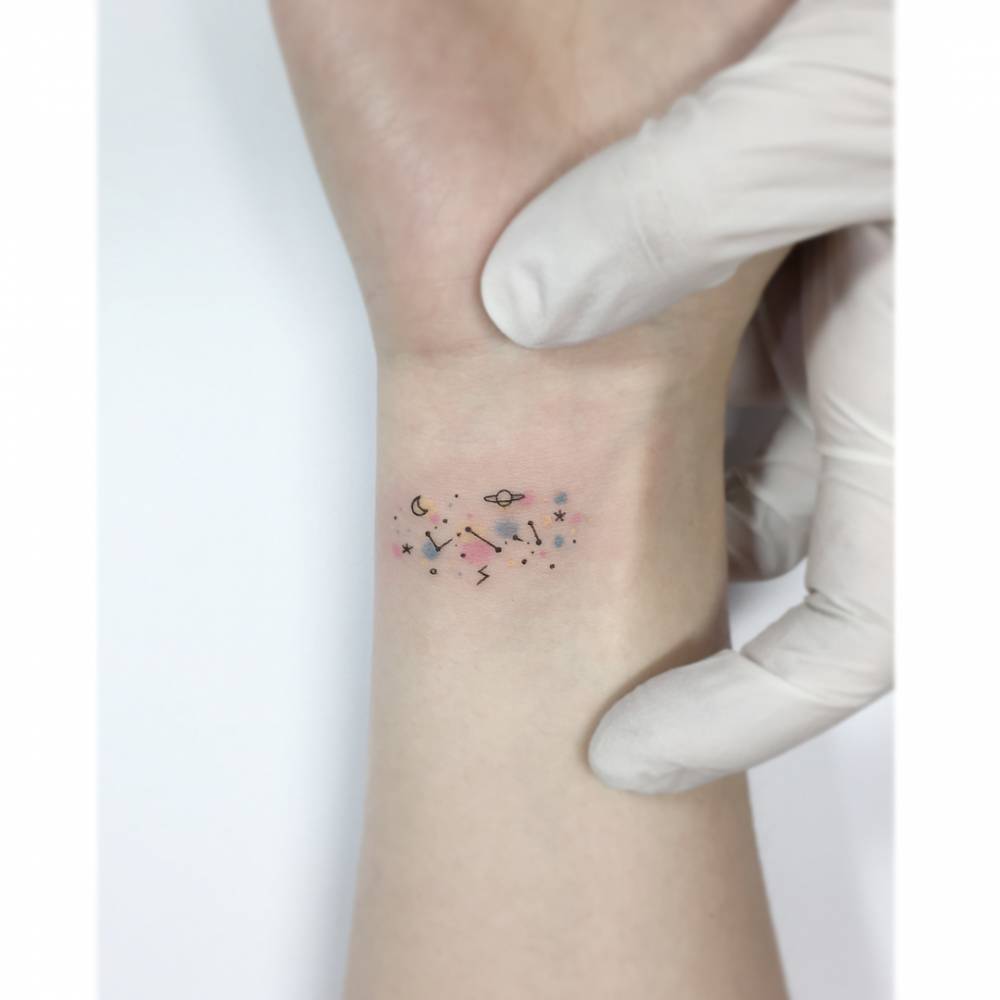 Tiny galaxy in minimalistic style tattooed on the wrist.
