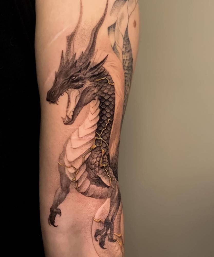 Kintsugi dragon tattooed on the upper arm.