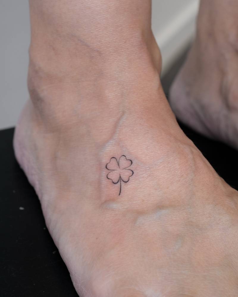 Minimalistic style four leaf clover tattoo located on the foot.