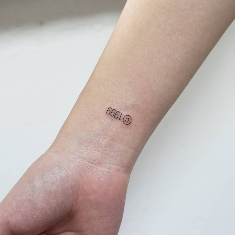 Copyright symbol and "1999" tattooed on the wrist.