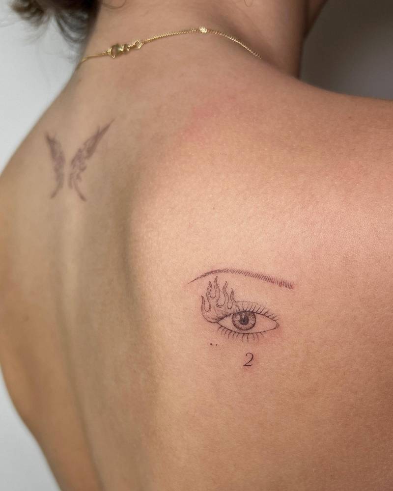 Single needle eye tattoo placed on the shoulder blade.