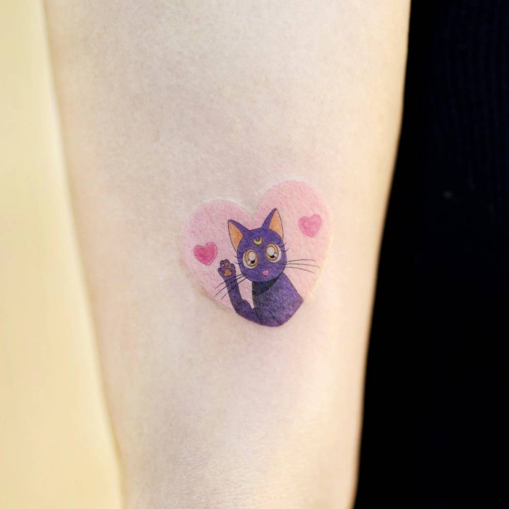 Jiji tattoo done on the upper forearm, cartoon style.