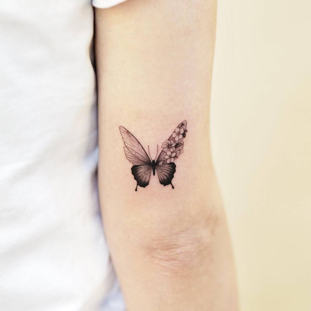 Illustrative style half butterfly half flowers tattoo located on the tricep.