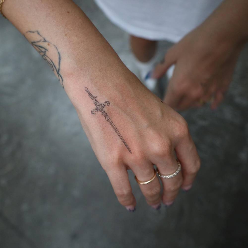 Single needle sword tattoo located on the hand.
