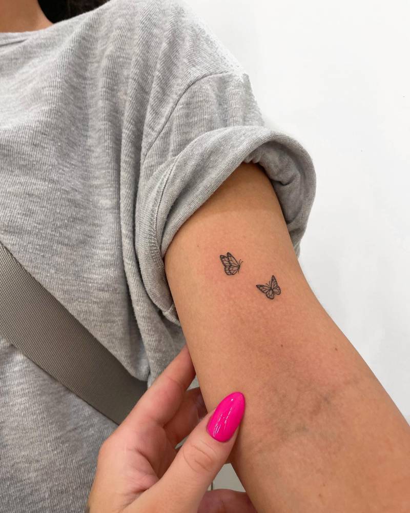 Butterfly couple tattoo located on the bicep, fine line style.