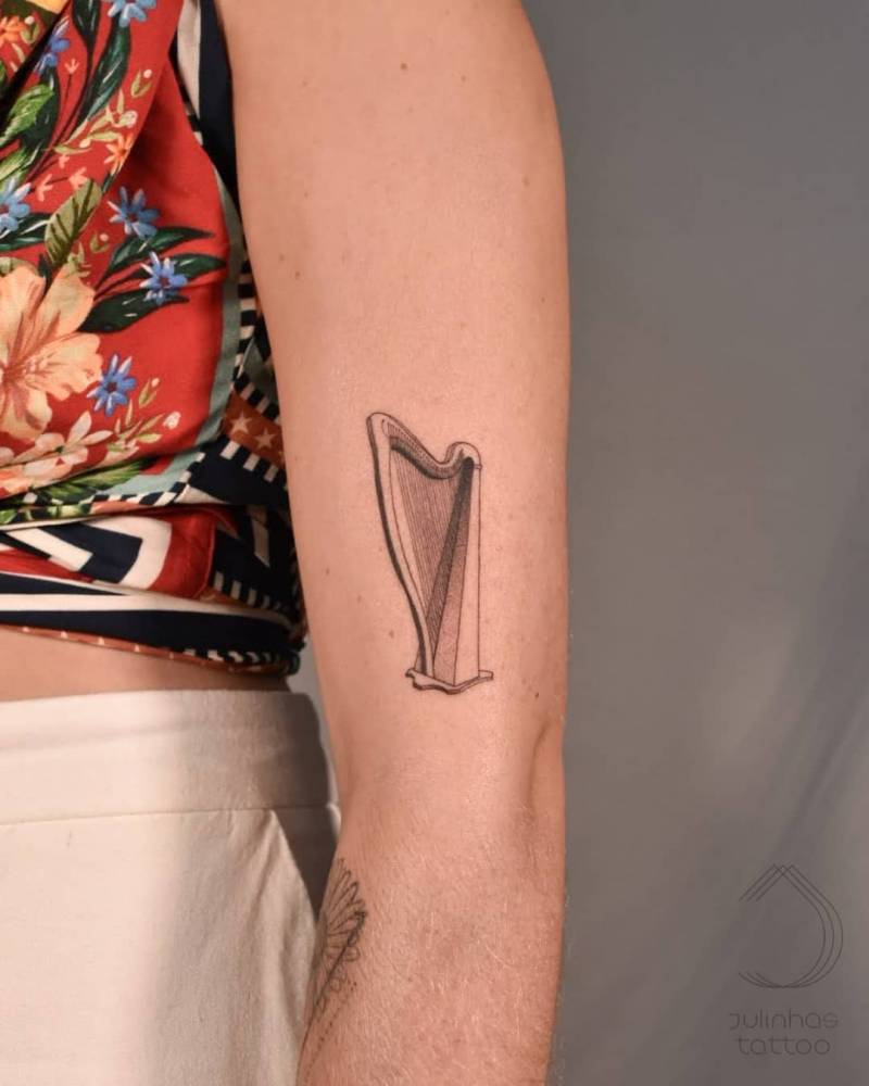 Harp tattoo in fine line, located on the upper arm.