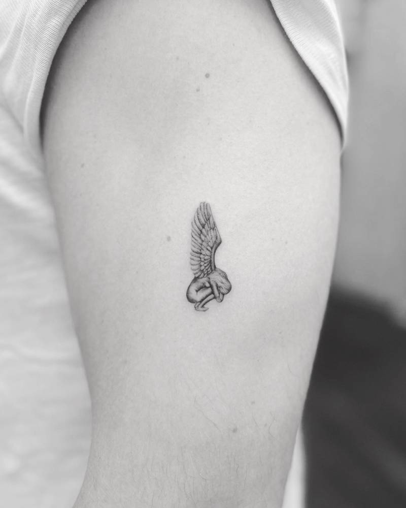 Fallen angel tattoo located on the upper arm, illustrative style.