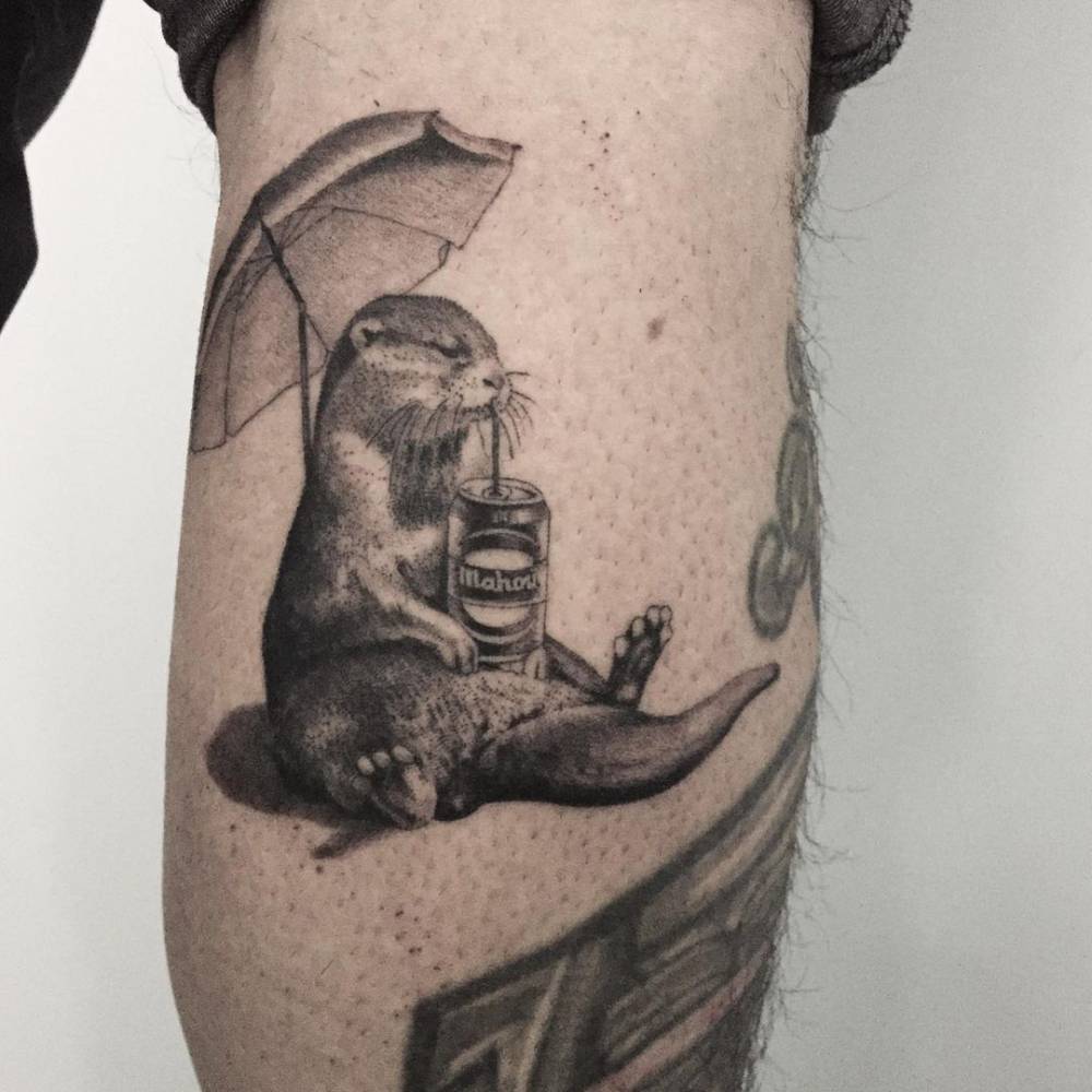 Micro-realistic otter drinking beer tattoo on the calf.