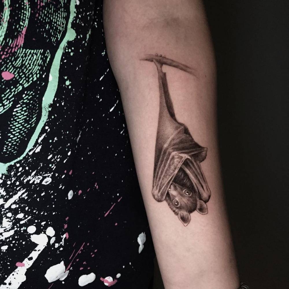 Micro-realistic bat tattoo on the inner forearm.