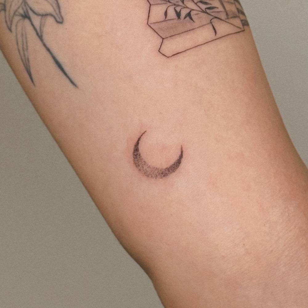 Dotwork style spectrum moon tattoo located on the inner arm.