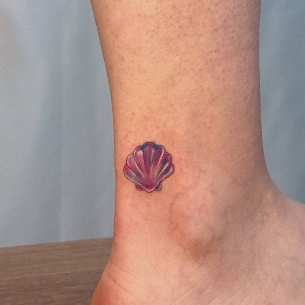 Scallop shell tattoo located on the ankle, done in illustrative style.