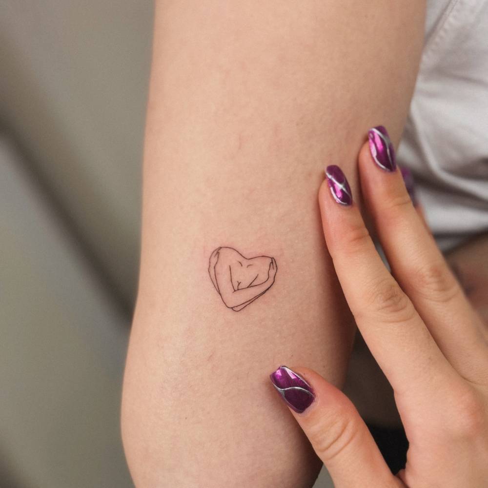 Self hug tattoo in fine line style located on the tricep.