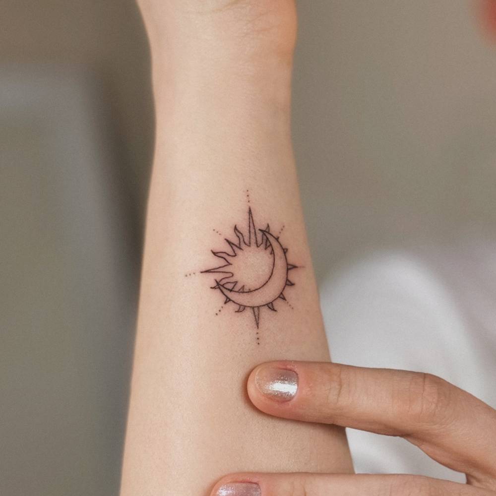 Sun and moon tattoo located on the wrist, fine line style.